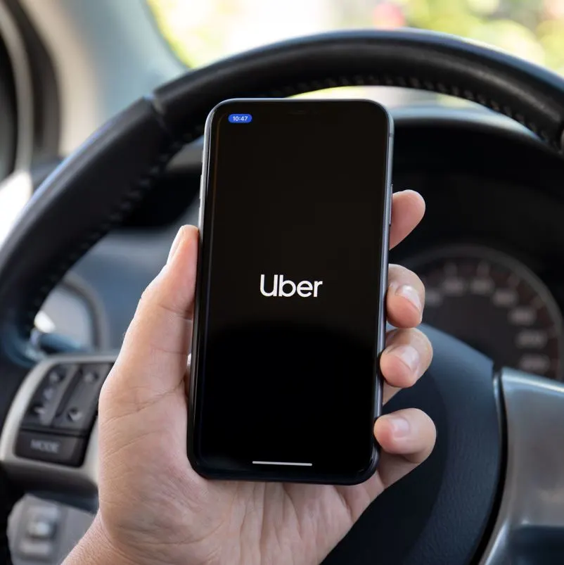 a man holding a phone with the uber app on it 