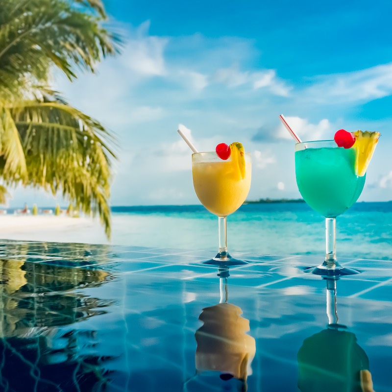 2 cocktails on a pool edge with the caribbean sea in the background