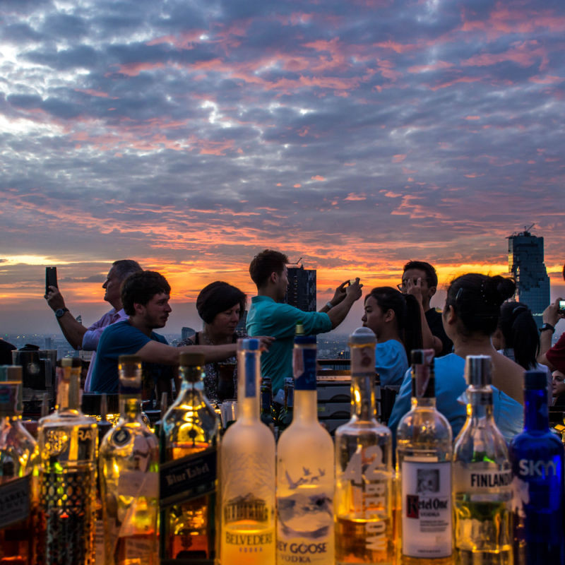Young people partying at a rooftop bar with drinks on the table