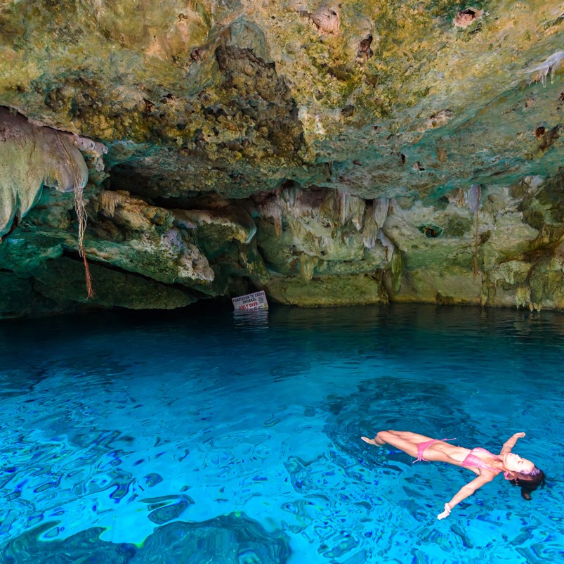 Lady floating in a cenote with blue water 