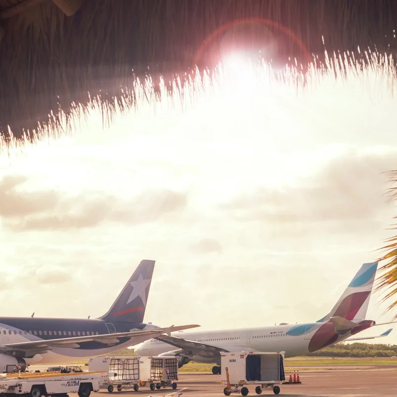 Punta Cana airport with tropical features and sunny weather, two aircraft parked outside 