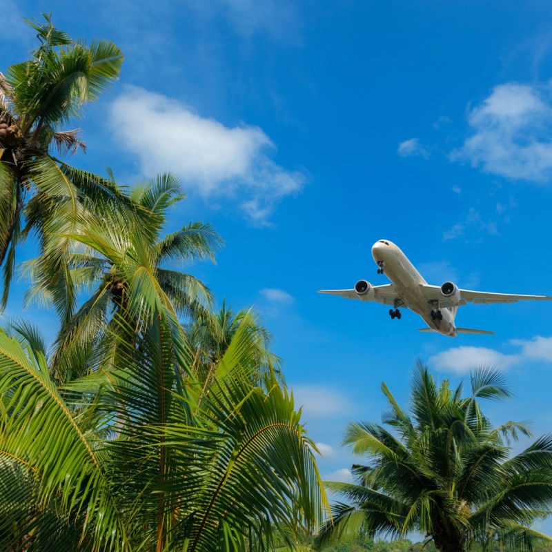 An airplane landing at a Caribbean airport amid tropical scenery