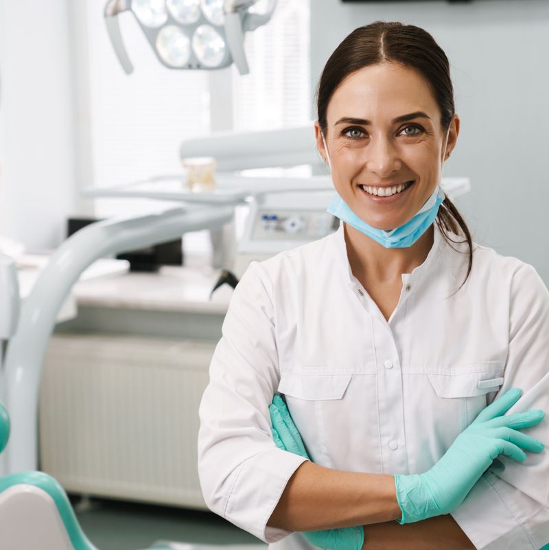 Dentist in her office smiles at the camera
