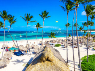 Landsape view of the Bavaro Beach in Punta Cana, with white sand, palm trees, umbrellas and turquoise water.