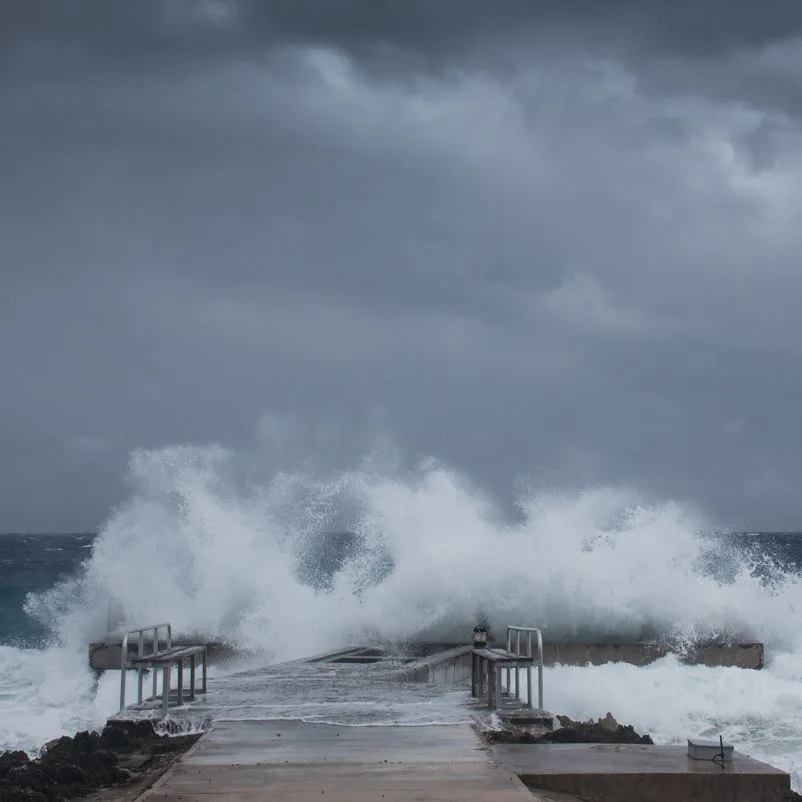 Large swells crash against a pier in the Caribbean