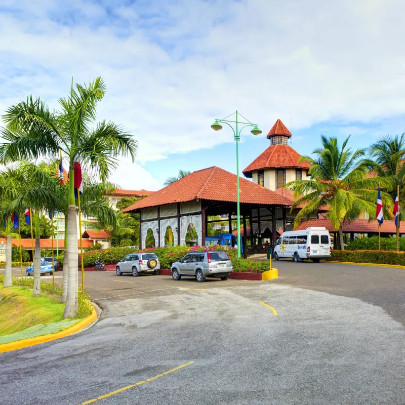 Bus and cars to the beautiful entrance of a Hotel with Palm Trees.