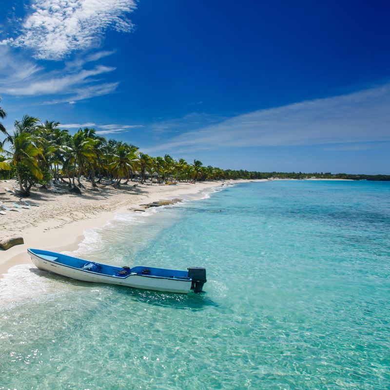 A beach in the dominican republic with a small boat along the shore and clear water