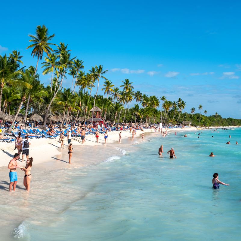 A tropical beach in the Dominican Republic with palm trees and travelers 