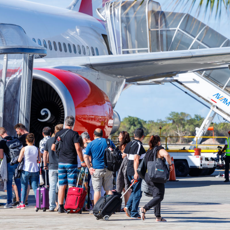 Travelers at Punta Cana airport next to a massive plane