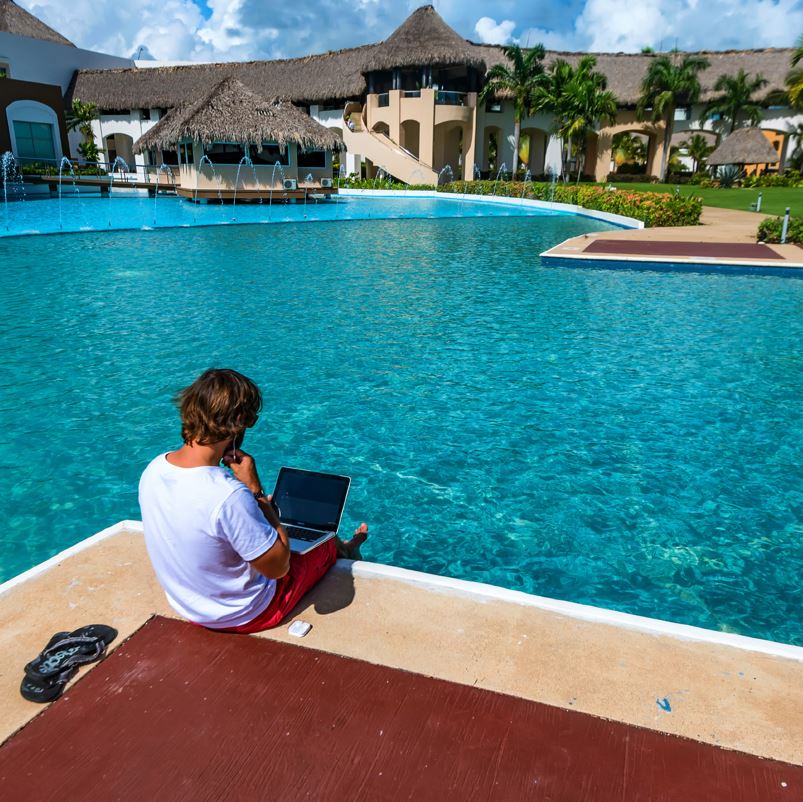 A traveler using their laptop by the pool in Punta Cana
