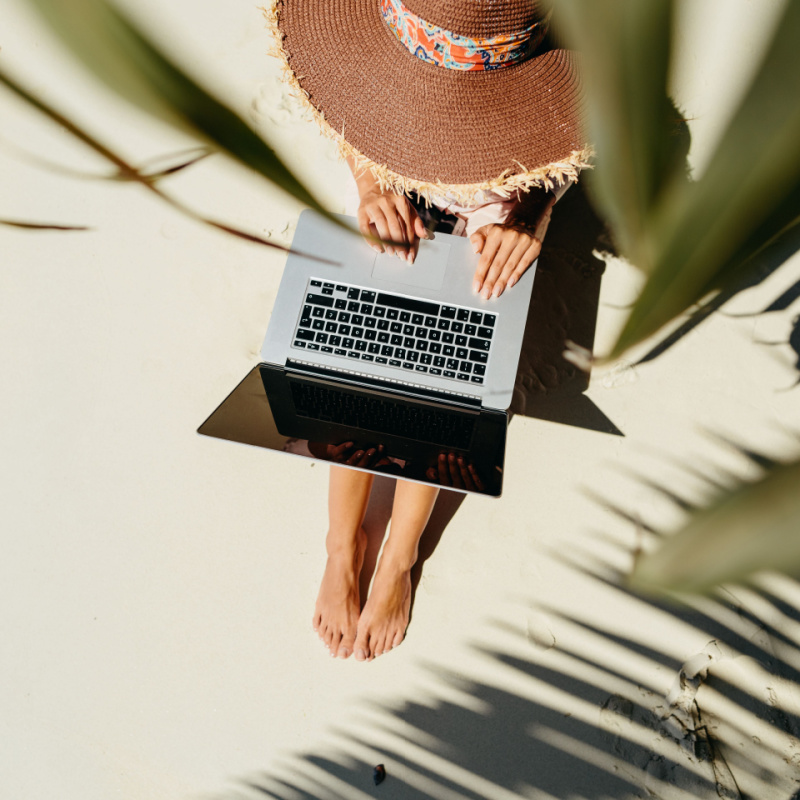 A digital nomad working on her laptop on a beach 