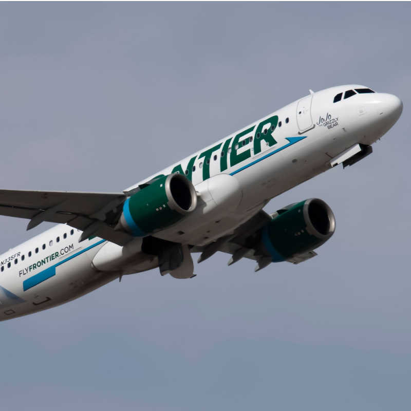 A frontier aircraft departing from a busy airport