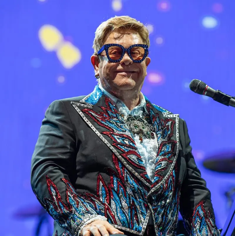 Elton john in flamboyant clothing and glasses