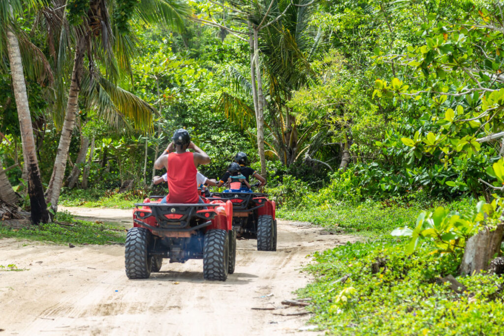 A tour group travels on ATVs on the beach